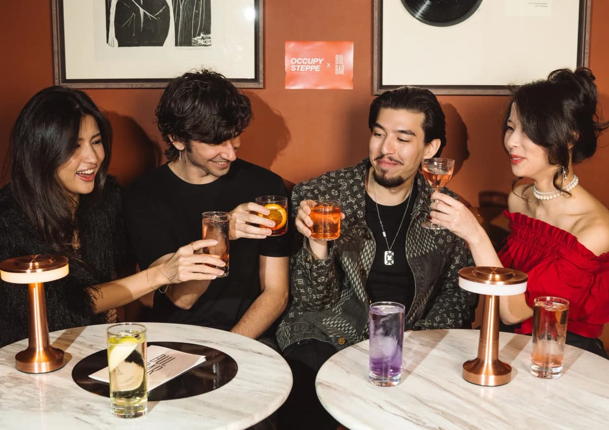 Friends toasting cocktails at a BUL BAR table